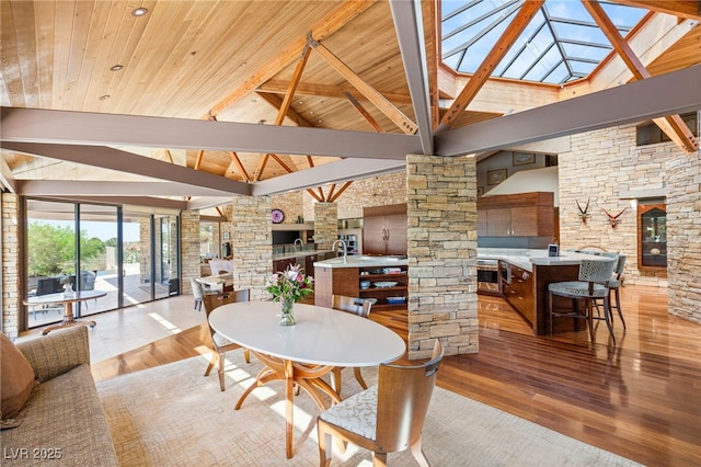 dining area with wooden ceiling, a fireplace, light wood-style floors, high vaulted ceiling, and decorative columns