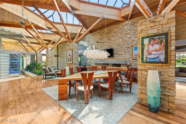 dining space with wood finished floors, a skylight, wood ceiling, beam ceiling, and high vaulted ceiling