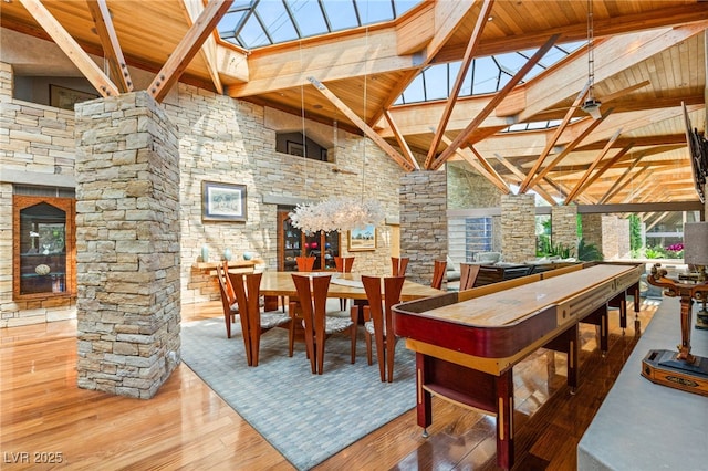 dining area with wooden ceiling, wood finished floors, a skylight, beam ceiling, and high vaulted ceiling
