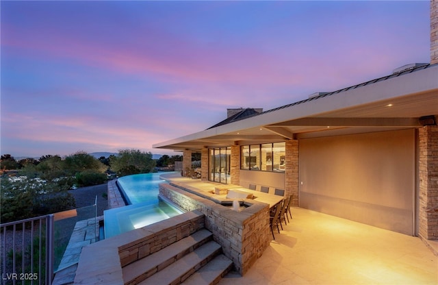 view of swimming pool with a patio, an infinity pool, an in ground hot tub, and outdoor dry bar