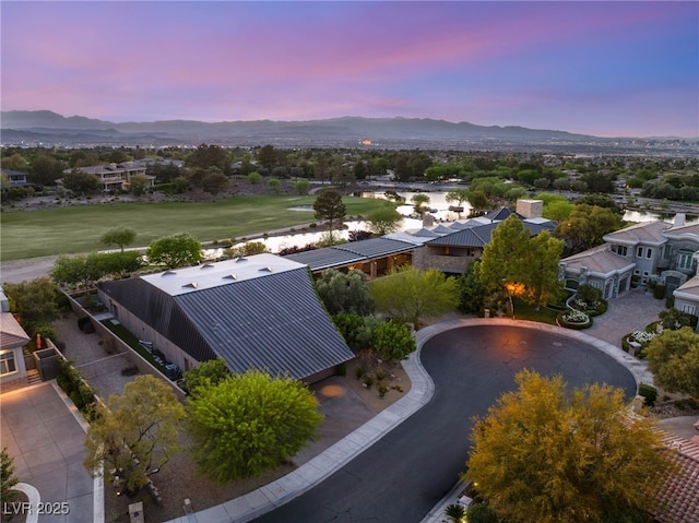 aerial view at dusk featuring a water and mountain view