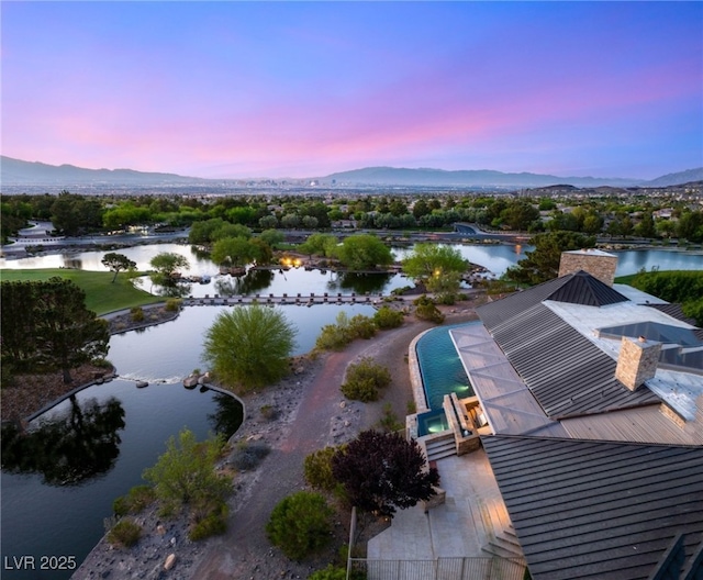 aerial view at dusk featuring a water and mountain view