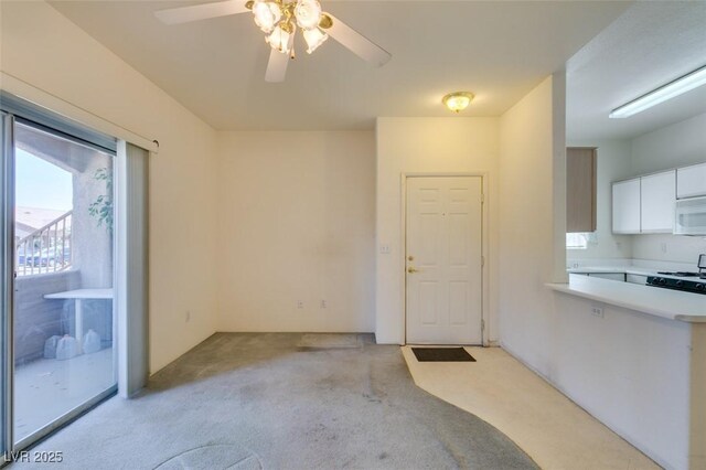 5751 E Hacienda Ave Unit 105, Las Vegas, NV 89122 - kitchen featuring light colored carpet, a ceiling fan, white cabinetry, light countertops, and white microwave