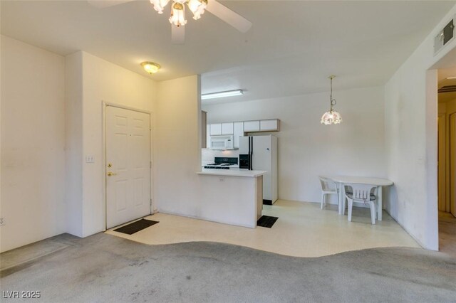 5751 E Hacienda Ave Unit 105, Las Vegas, NV 89122 - kitchen featuring white appliances, light carpet, a ceiling fan, and a peninsula
