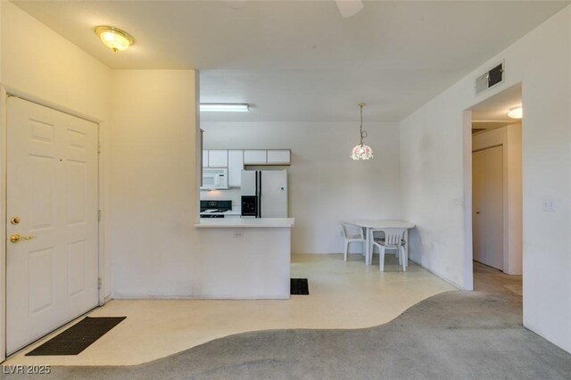 5751 E Hacienda Ave Unit 105, Las Vegas, NV 89122 - kitchen with white appliances, white cabinetry, a peninsula, light carpet, and pendant lighting
