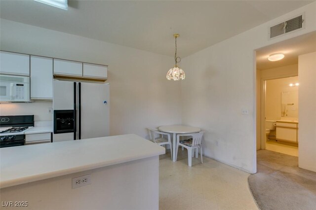 5751 E Hacienda Ave Unit 105, Las Vegas, NV 89122 - kitchen with white appliances, white cabinets, hanging light fixtures, light countertops, and a chandelier