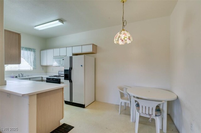 5751 E Hacienda Ave Unit 105, Las Vegas, NV 89122 - kitchen featuring white appliances, light countertops, a peninsula, decorative light fixtures, and light flooring