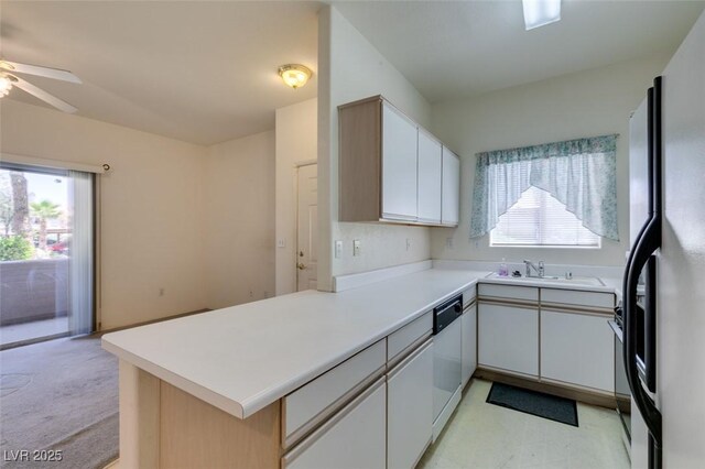 kitchen with a sink, dishwasher, light countertops, black refrigerator with ice dispenser, and a peninsula