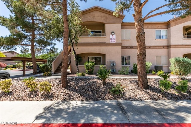 view of front of home featuring central air condition unit, stucco siding, and stairway