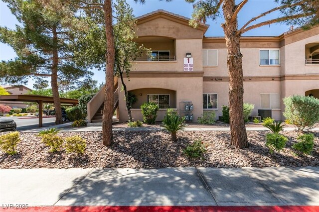 5751 E Hacienda Ave Unit 105, Las Vegas, NV 89122 - view of front of home with stairway, cooling unit, and stucco siding