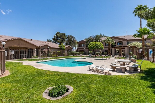 community pool with fence, a lawn, and a patio area