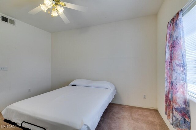 bedroom featuring a ceiling fan, visible vents, multiple windows, and light carpet
