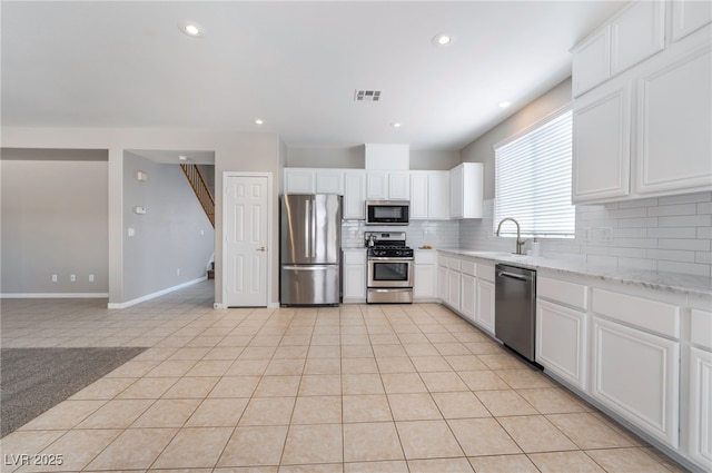 kitchen featuring visible vents, light tile patterned flooring, tasteful backsplash, a sink, and appliances with stainless steel finishes