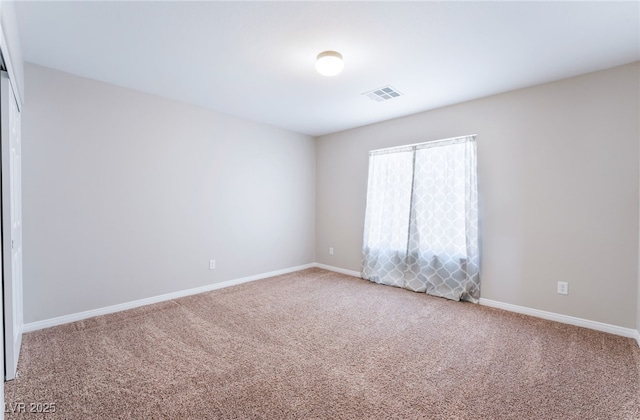 carpeted spare room featuring visible vents and baseboards