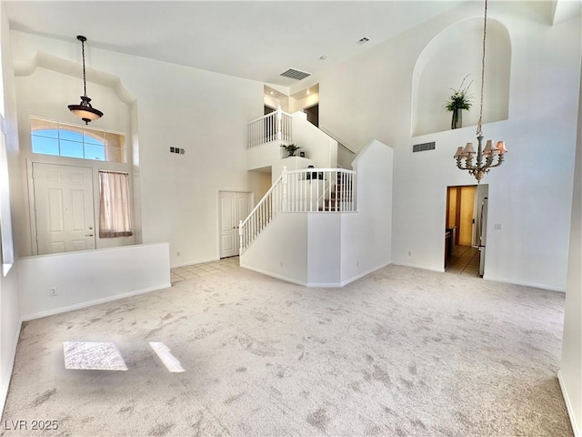 unfurnished living room featuring visible vents, a towering ceiling, and carpet floors