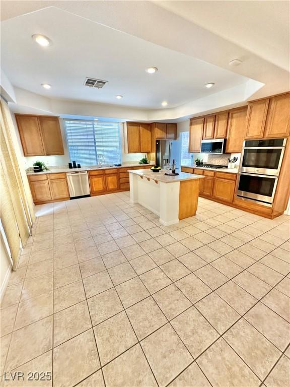 kitchen featuring visible vents, appliances with stainless steel finishes, light countertops, light tile patterned floors, and a sink