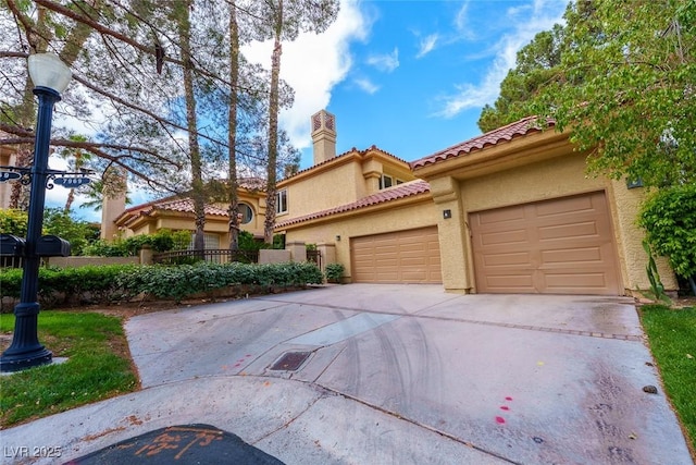 mediterranean / spanish house featuring a chimney, stucco siding, a tile roof, driveway, and an attached garage