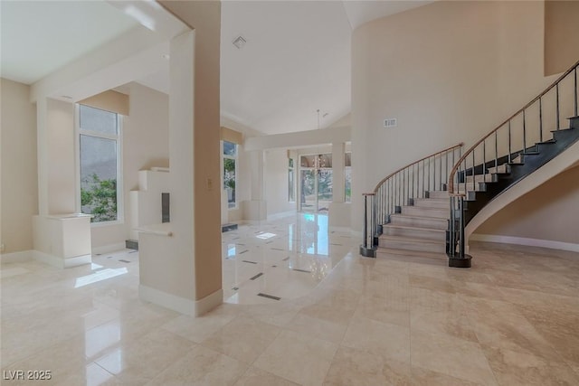 entrance foyer with stairway, high vaulted ceiling, and baseboards