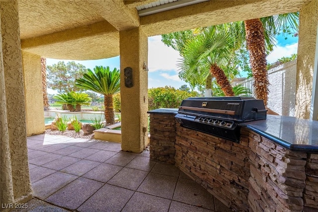 view of patio featuring a grill, a fenced backyard, an outdoor pool, and exterior kitchen