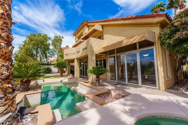 rear view of house with a patio, an in ground hot tub, a fenced in pool, a tiled roof, and stucco siding