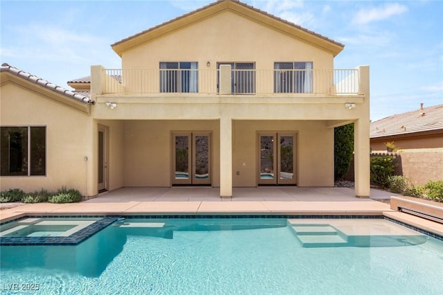 17 Morninglow Pass, Henderson, NV 89052 - rear view of house featuring a patio, a pool with connected hot tub, a balcony, stucco siding, and french doors