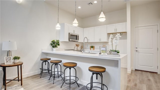 1187 Blossom Point St Unit 36, Las Vegas, NV 89135 - kitchen with stainless steel microwave, a sink, a kitchen bar, visible vents, and light countertops