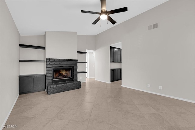 unfurnished living room with a brick fireplace, light tile patterned floors, a ceiling fan, visible vents, and baseboards