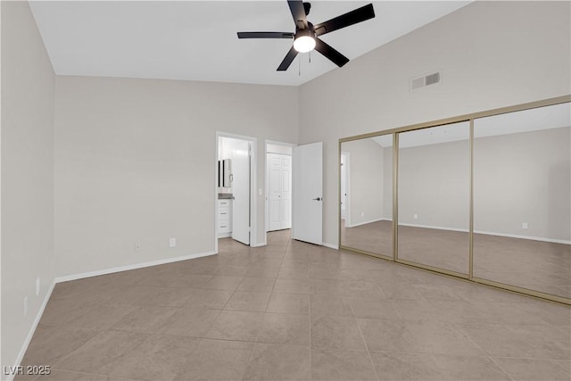 unfurnished bedroom featuring lofted ceiling, visible vents, baseboards, a ceiling fan, and ensuite bath