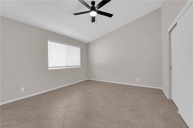 empty room featuring ceiling fan, vaulted ceiling, and baseboards