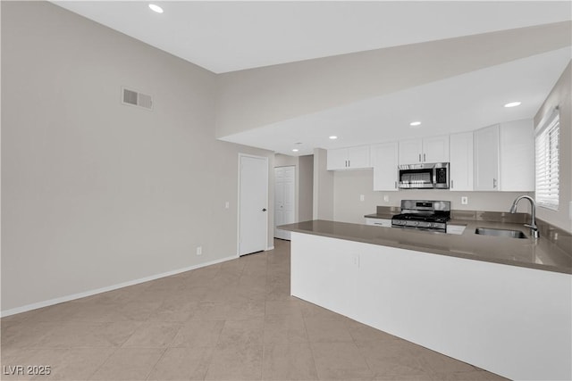 kitchen featuring white cabinetry, a sink, appliances with stainless steel finishes, visible vents, and a peninsula