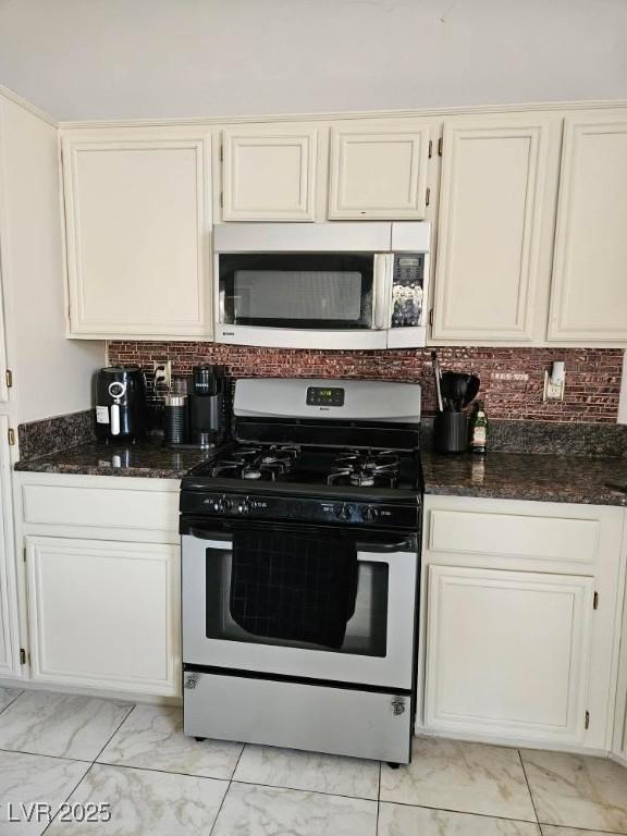 kitchen with dark stone countertops, tasteful backsplash, stainless steel appliances, and marble finish floor
