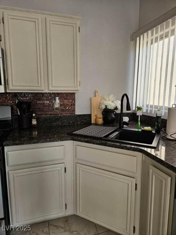 kitchen featuring electric stove, a sink, tasteful backsplash, marble finish floor, and white cabinets