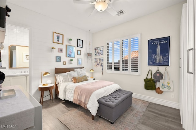 bedroom with baseboards, connected bathroom, wood finished floors, and visible vents