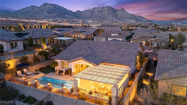 rear view of property featuring a tiled roof, a mountain view, a fenced backyard, and stucco siding