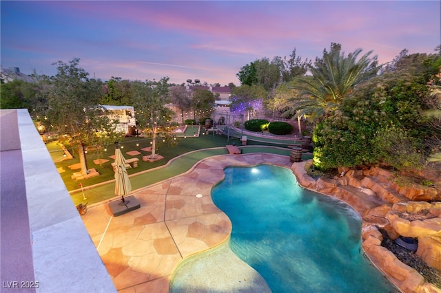 pool at dusk featuring a patio and an outdoor pool