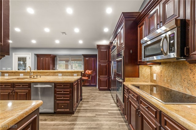 kitchen featuring a sink, visible vents, light wood-style flooring, reddish brown cabinets, and appliances with stainless steel finishes