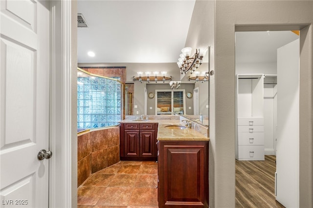 bathroom with visible vents, a tile shower, double vanity, and a sink