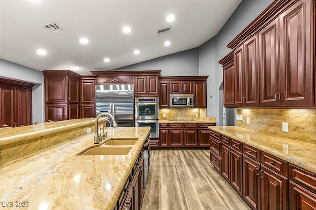 kitchen with a sink, appliances with stainless steel finishes, light wood-style floors, visible vents, and dark brown cabinets