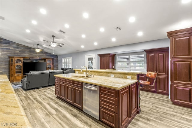 kitchen featuring stainless steel dishwasher, reddish brown cabinets, a sink, and visible vents