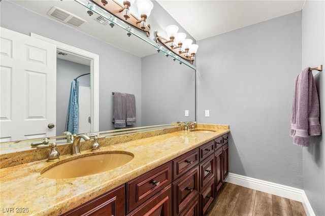 bathroom featuring a sink, baseboards, wood finished floors, and visible vents