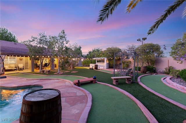 yard at dusk featuring an outdoor pool and a patio