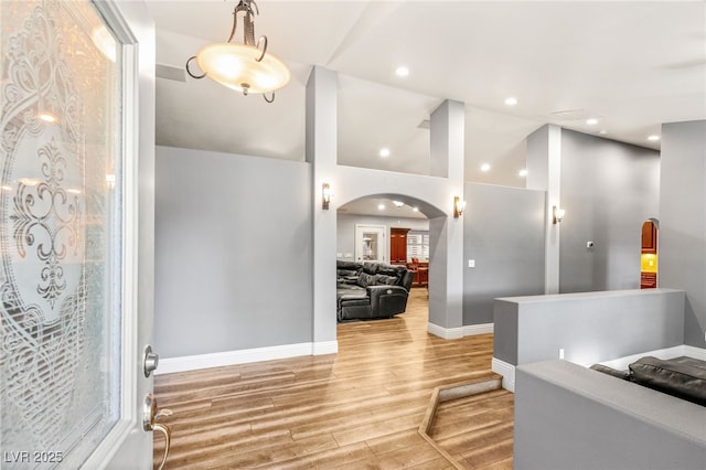 foyer with recessed lighting, arched walkways, light wood-style flooring, and baseboards