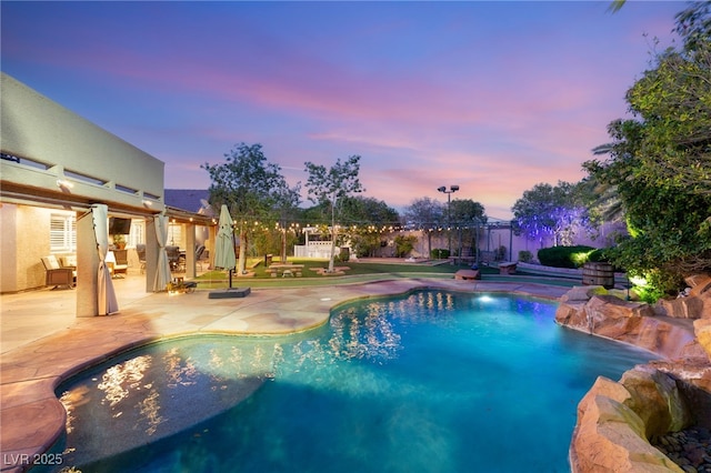 pool at dusk with a patio, fence, and an outdoor pool