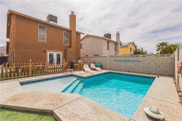 view of pool with a fenced backyard, central air condition unit, french doors, and a fenced in pool