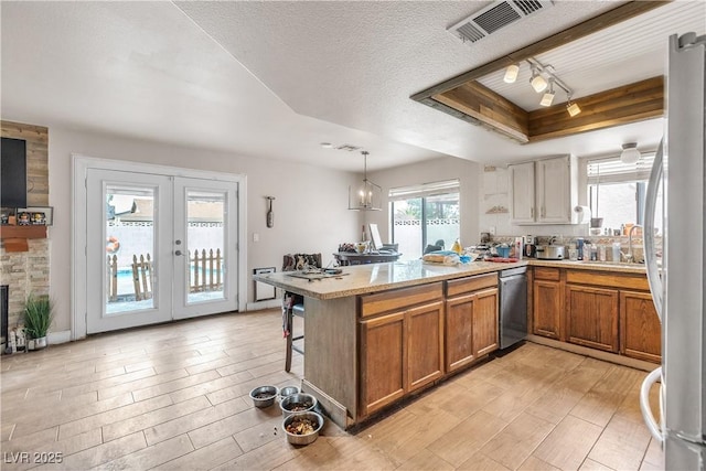 kitchen with stainless steel appliances, brown cabinetry, a peninsula, light countertops, and french doors