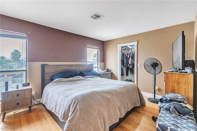 bedroom with a spacious closet, hardwood / wood-style floors, a closet, baseboards, and visible vents