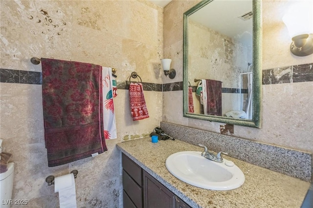 bathroom featuring walk in shower, tile walls, and vanity