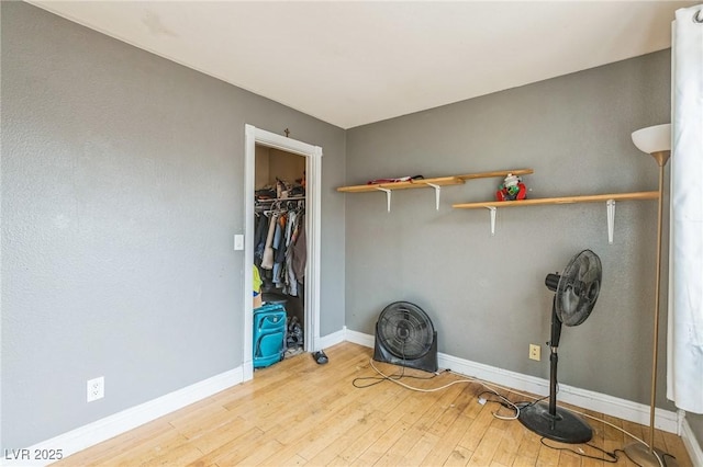 unfurnished bedroom with a closet, hardwood / wood-style flooring, and baseboards