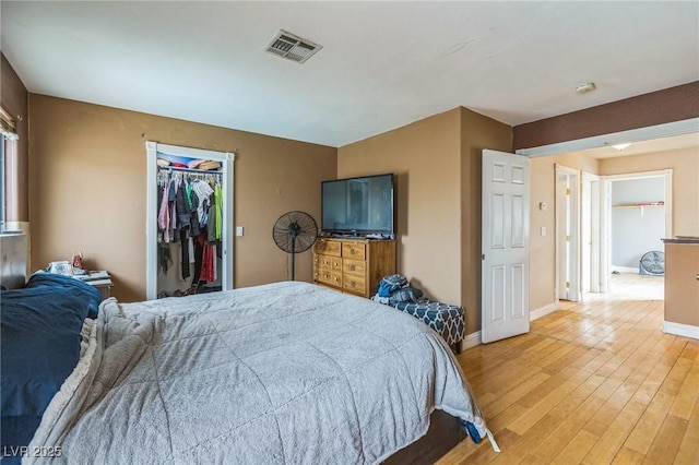 bedroom featuring a walk in closet, visible vents, baseboards, and light wood-style floors