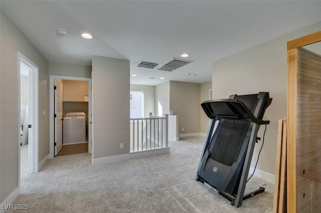 exercise room with baseboards, visible vents, washer / dryer, and light carpet